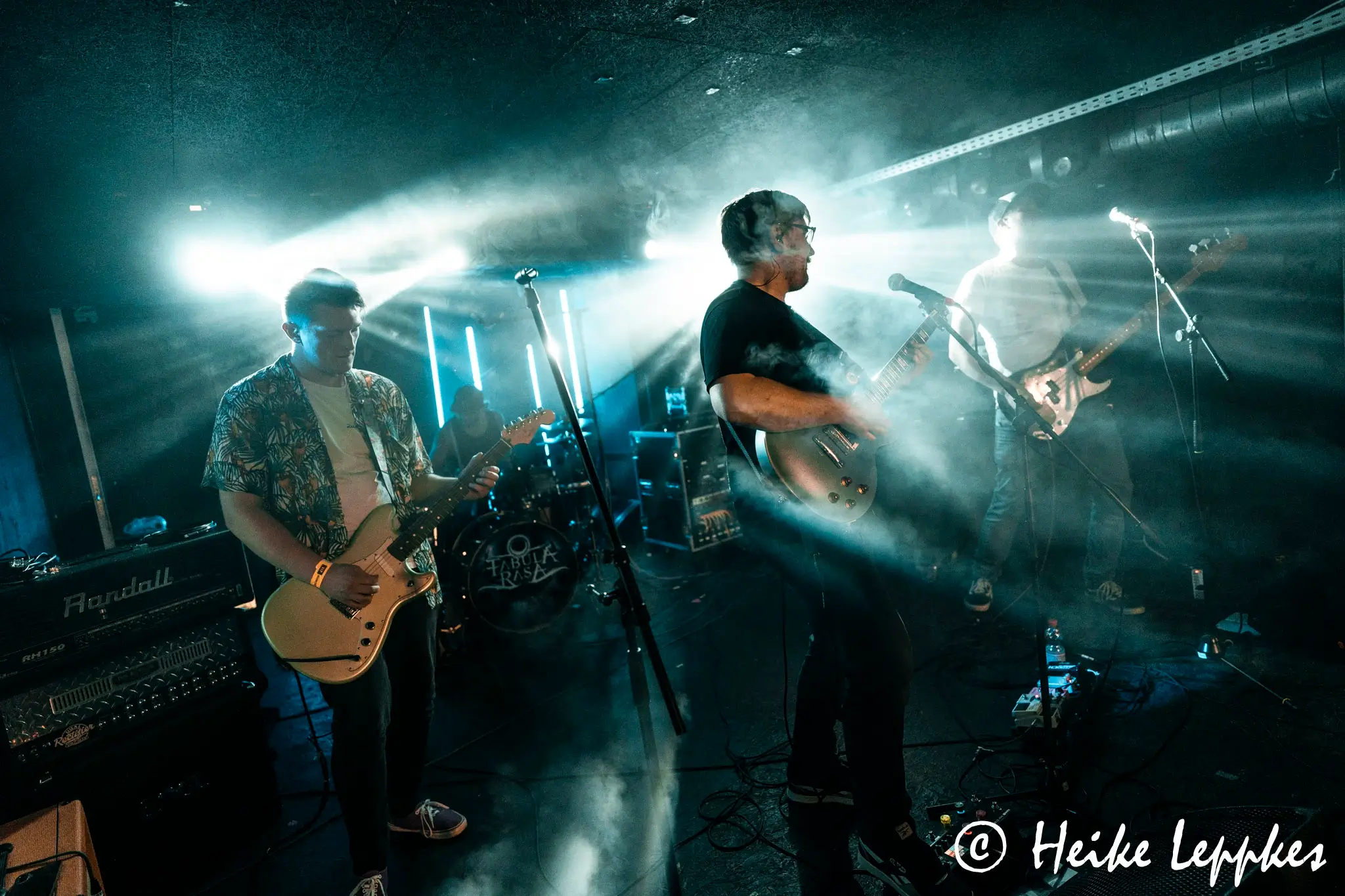 Kip Kasper live im MTC Köln – die Rockband spielt auf der Bühne mit E-Gitarren, E-Bass und Drums, während das Bühnenlicht ihre Schatten wirft.